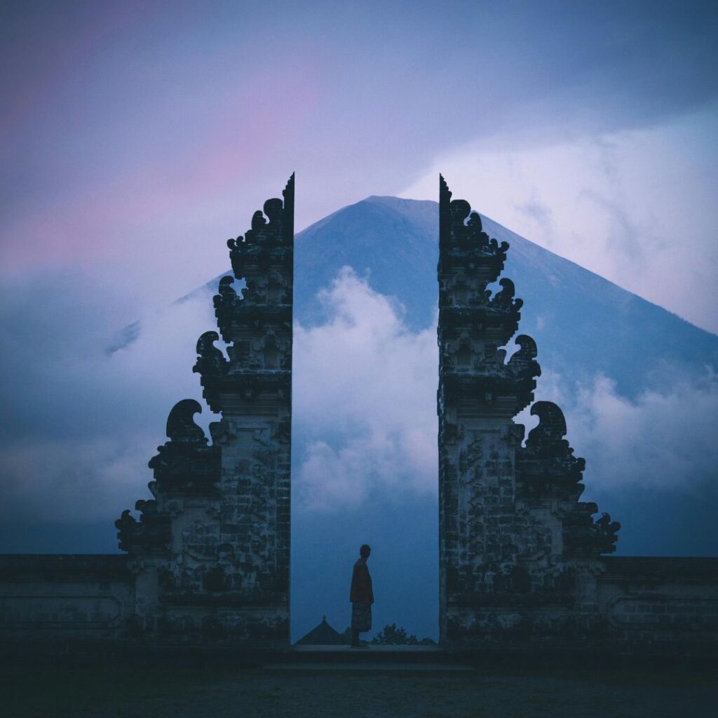 Person standing at Lempuyang Temple at night, with the temple’s illuminated gates and starry sky creating a mystical atmosphere—an enchanting setting for romantic getaways for couples.
