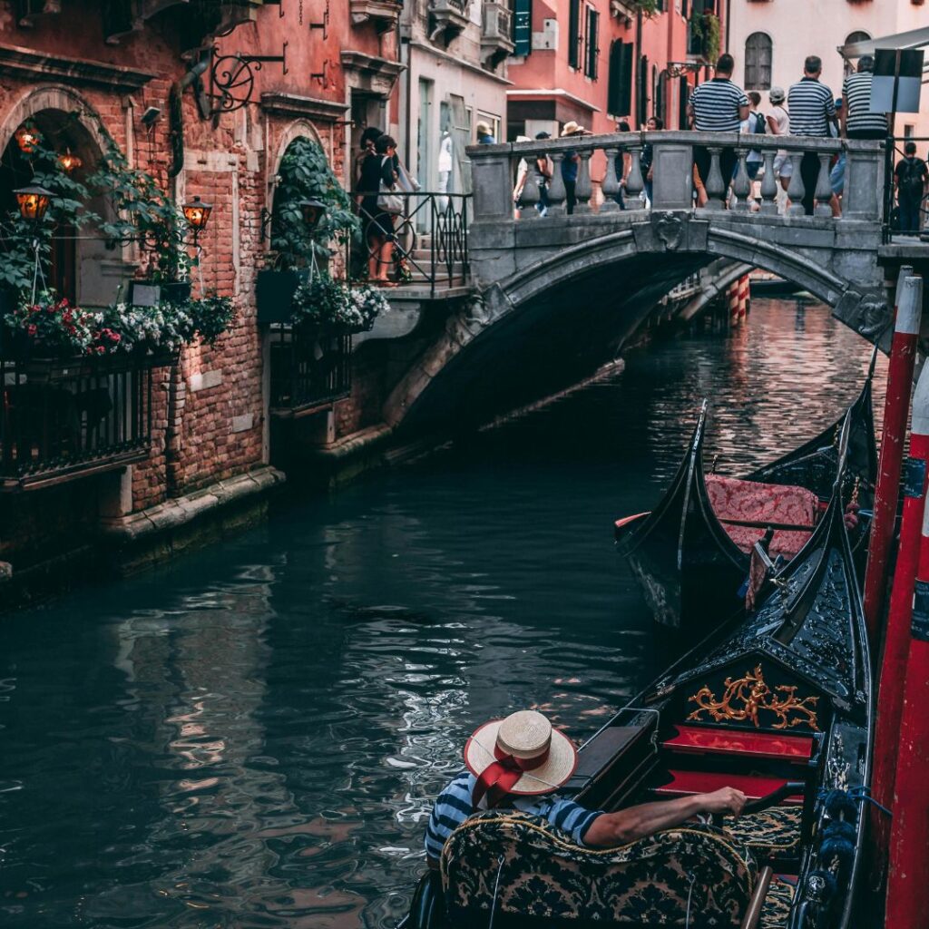 Charming canal in Venice with a gondola gliding through the serene waters, featuring a person enjoying a romantic boat ride, perfect for anniversary trip ideas amidst historic buildings and picturesque reflections