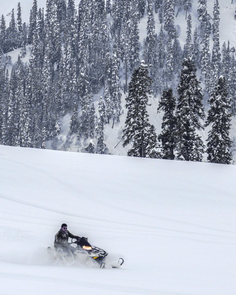 A person enjoying motor skiing on the snow-covered slopes of Gulmarg, one of the top winter tourist destinations in India. Surrounded by breathtaking Himalayan peaks, the scene captures the thrill and adventure of winter sports in this popular ski resort.